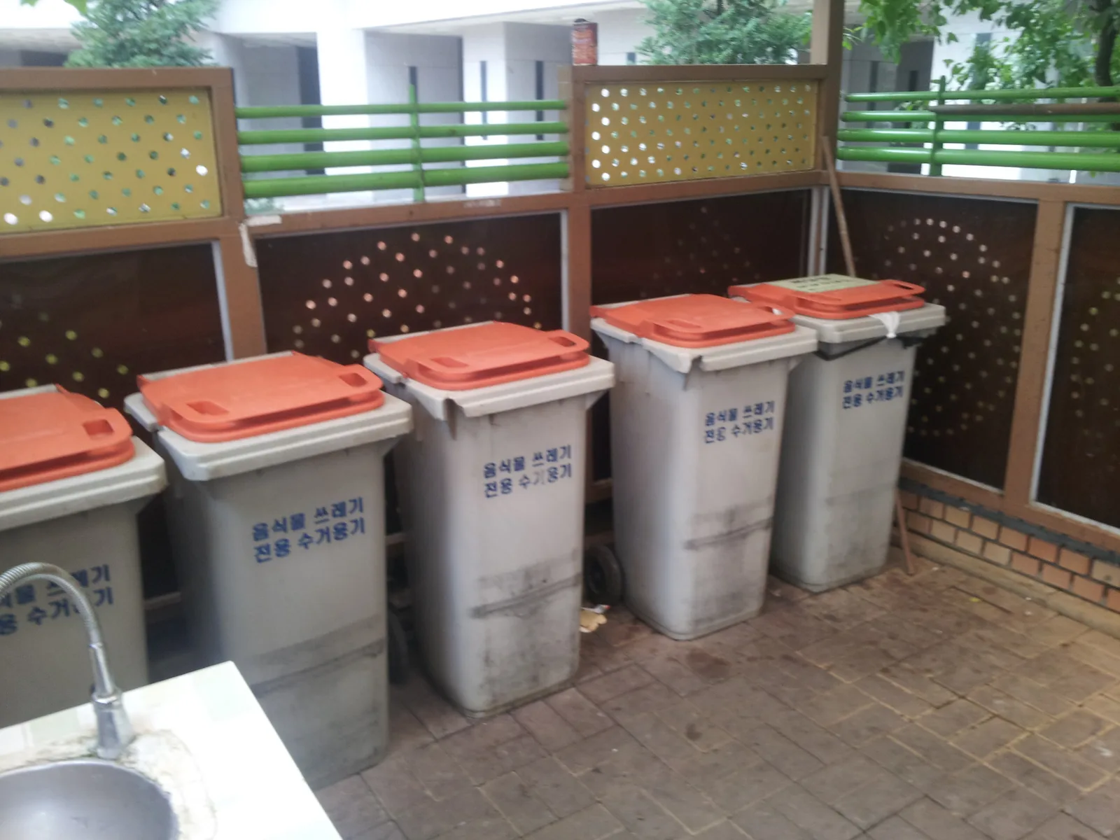Food-waste collection bins with orange lids lined up at an apartment complex in Korea